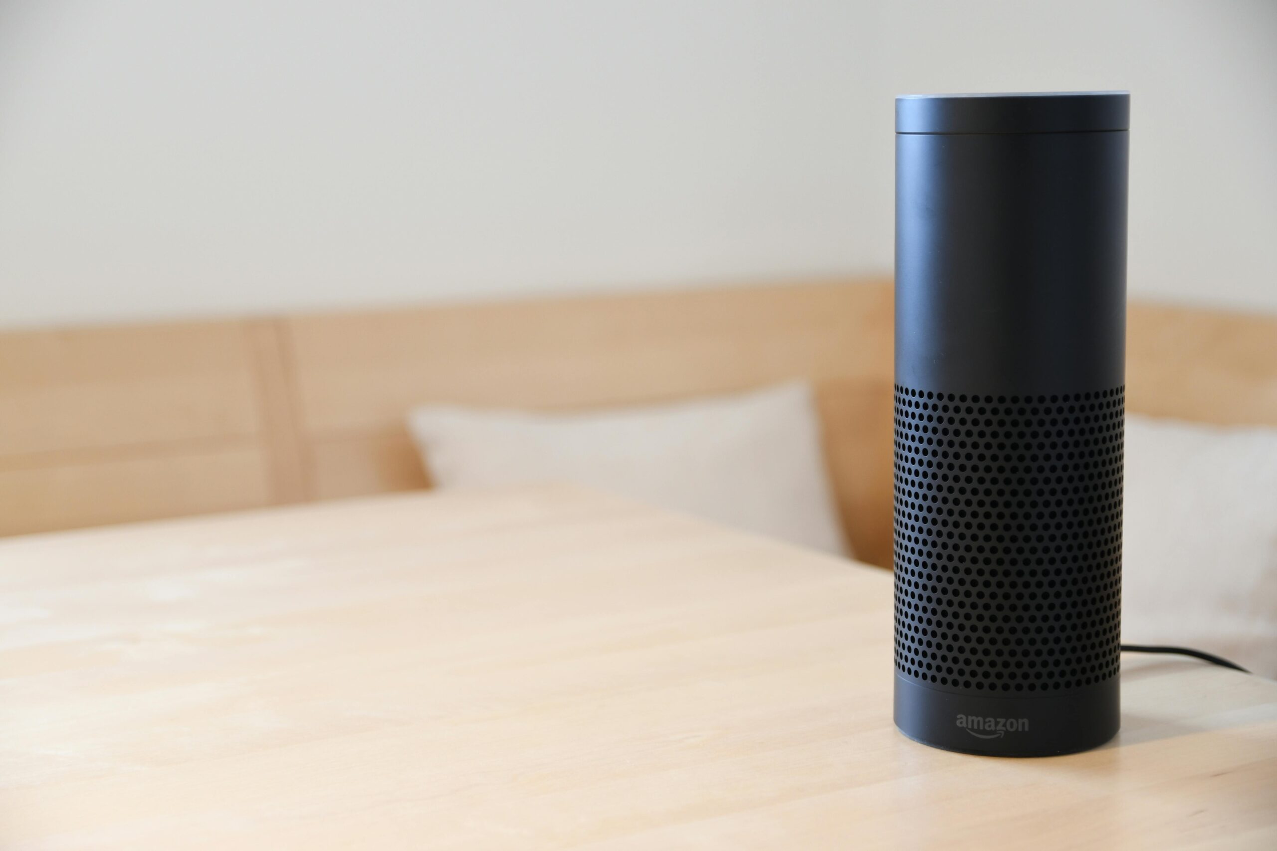 Czarny głośnik Amazon Echo z asystentem Alexa stojący na jasnym stole w nowoczesnym salonie – integracja urządzeń smart home