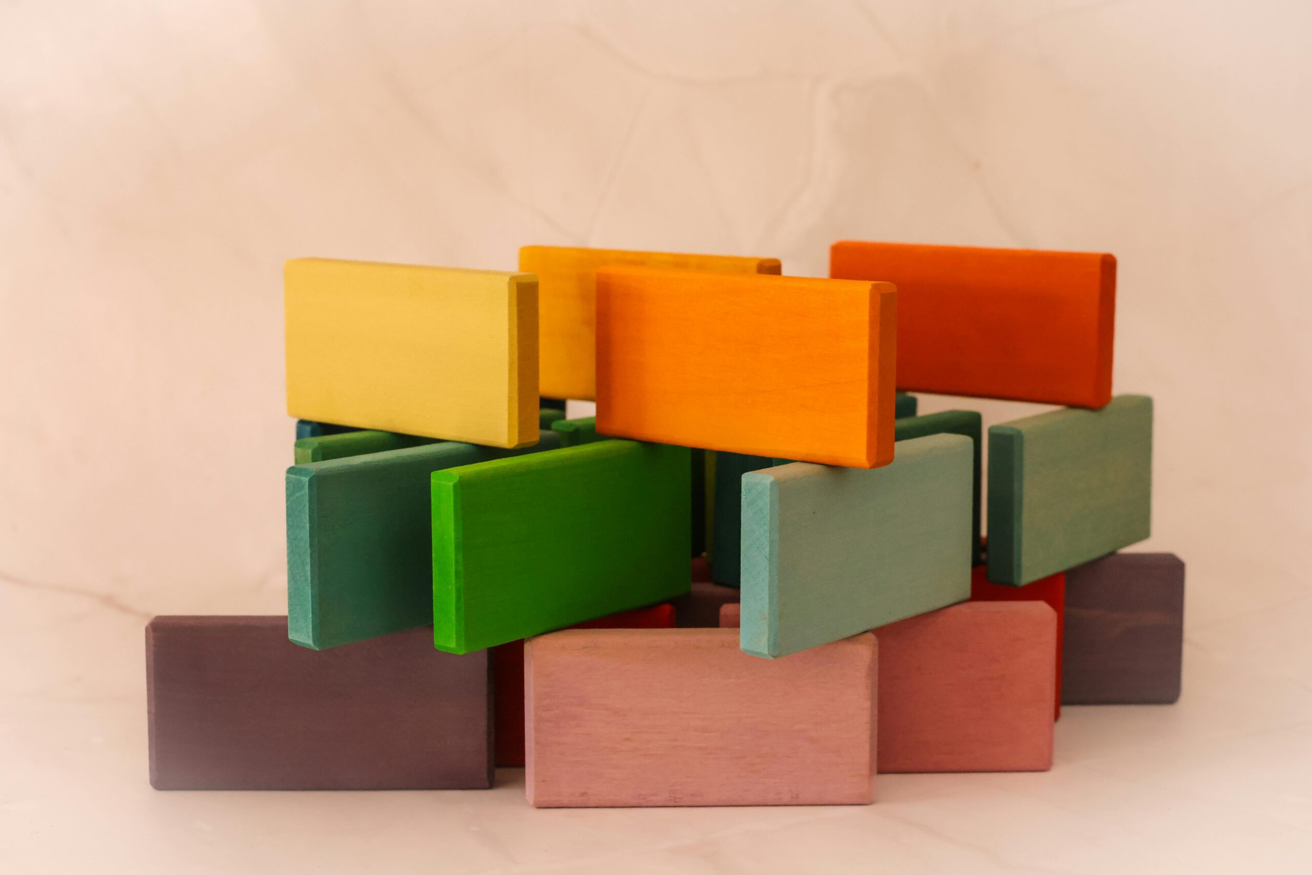 Kolorowe drewniane klocki ustawione w geometryczną konstrukcję na jasnym tle.