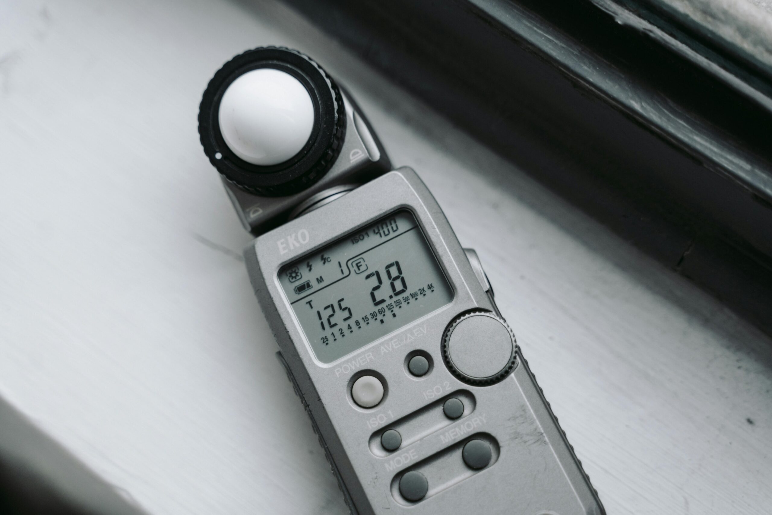 Cyfrowy luksomierz leżący na parapecie, służący do precyzyjnego mierzenia natężenia światła w luksach.